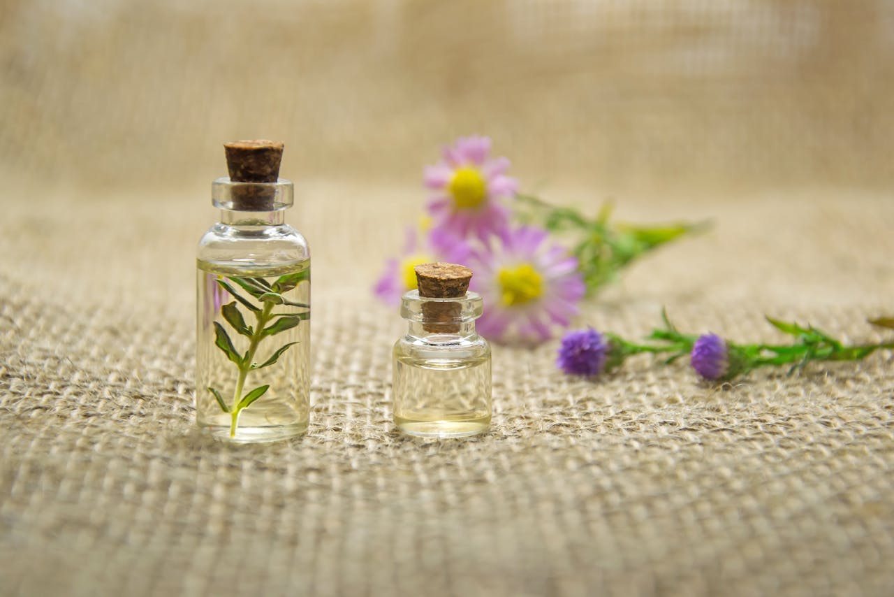 services-04 Glass bottles with essential oils and fresh flowers on burlap fabric creating a natural aroma.