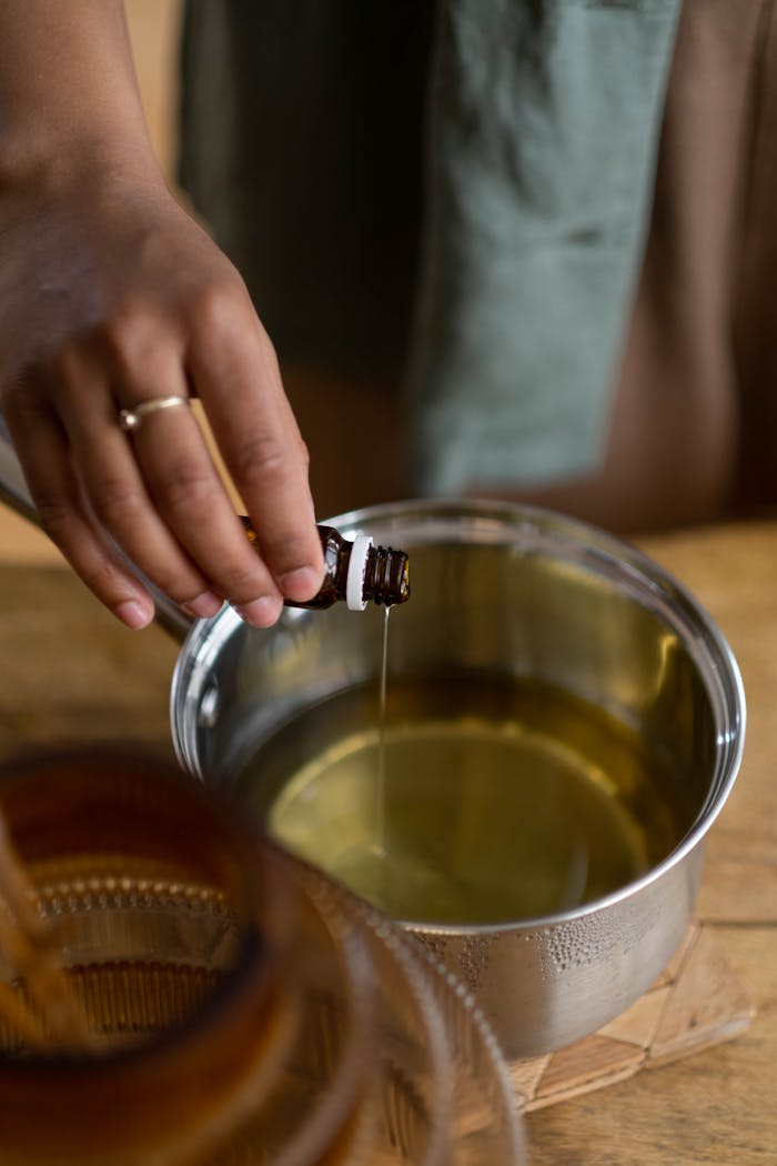 services-03 A hand drips essential oil into a pot, emphasizing DIY and aromatherapy indoors.